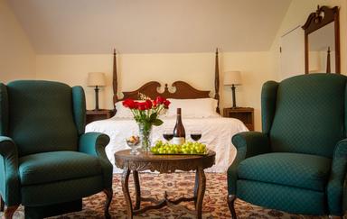 Preview of The Cottage interior with a bed in the background, and two armchairs and a table in the foreground
