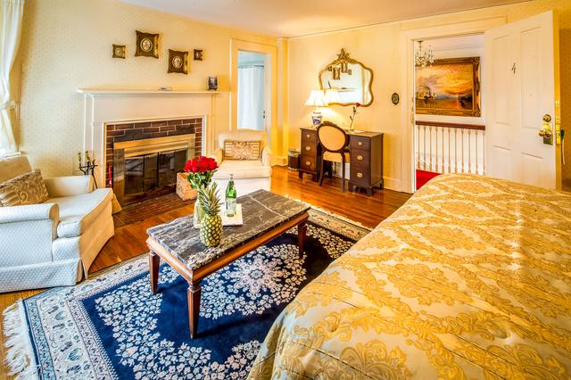 View of a Main House Room with bed, and two chairs in front of a fireplace, as well as a table