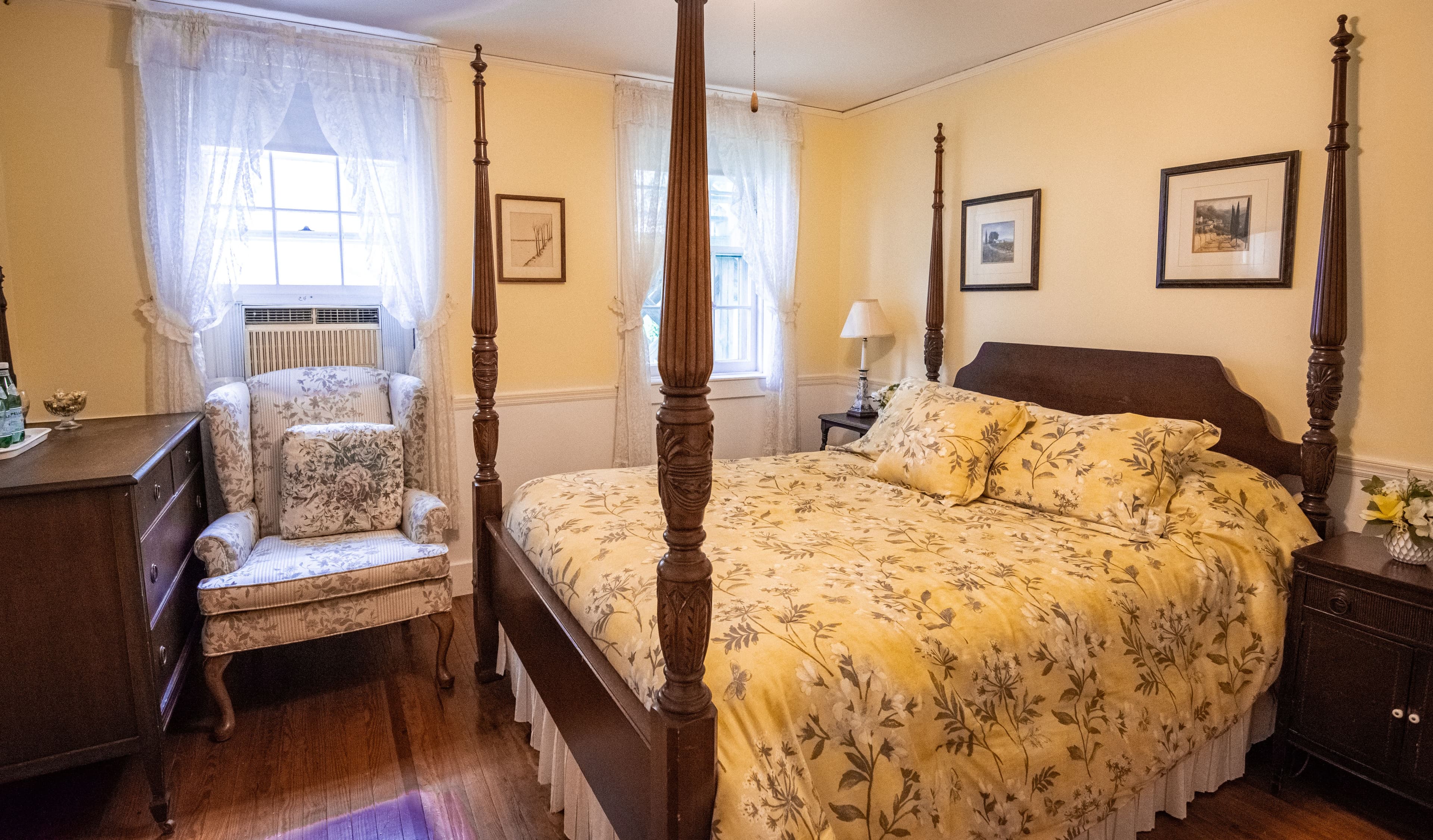 Carriage House room with bed and an armchair in front of one of two windows